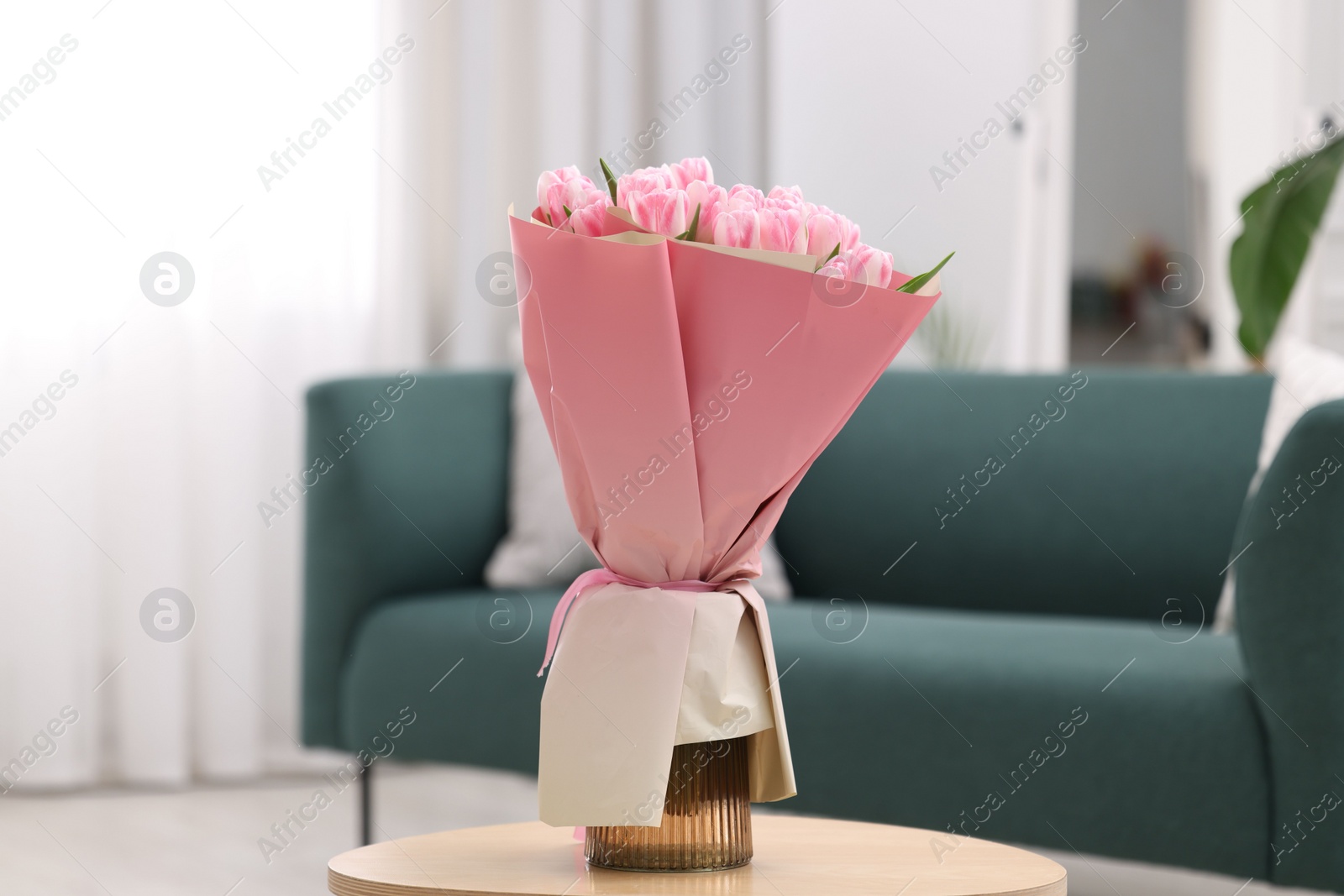 Photo of Beautiful bouquet of fresh pink tulips on table at home