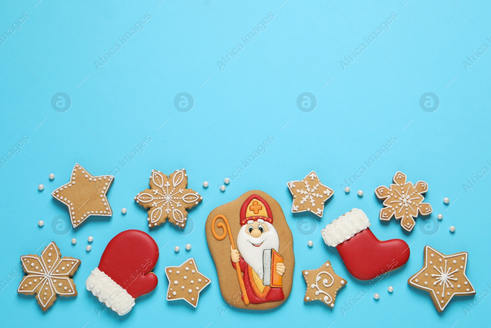 Photo of Tasty gingerbread cookies on light blue background, flat lay with space for text. St. Nicholas Day celebration