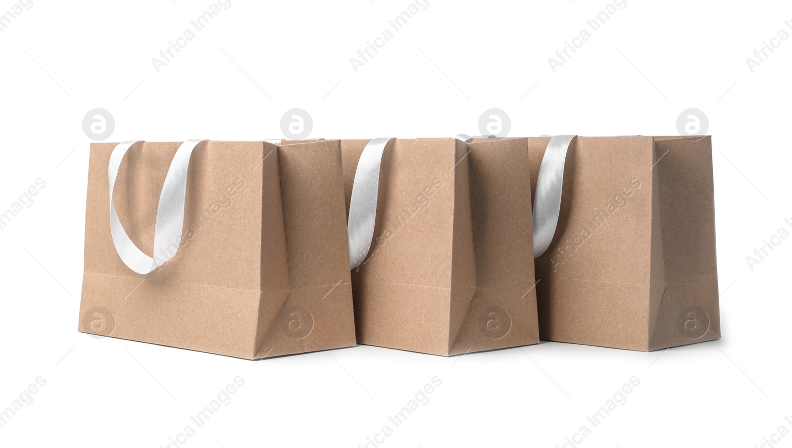 Photo of Paper shopping bags with ribbon handles on white background. Mockup for design