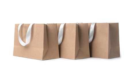 Photo of Paper shopping bags with ribbon handles on white background. Mockup for design