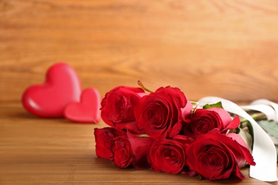 Beautiful red roses with white ribbon on wooden table, space for text. Valentine's Day celebration