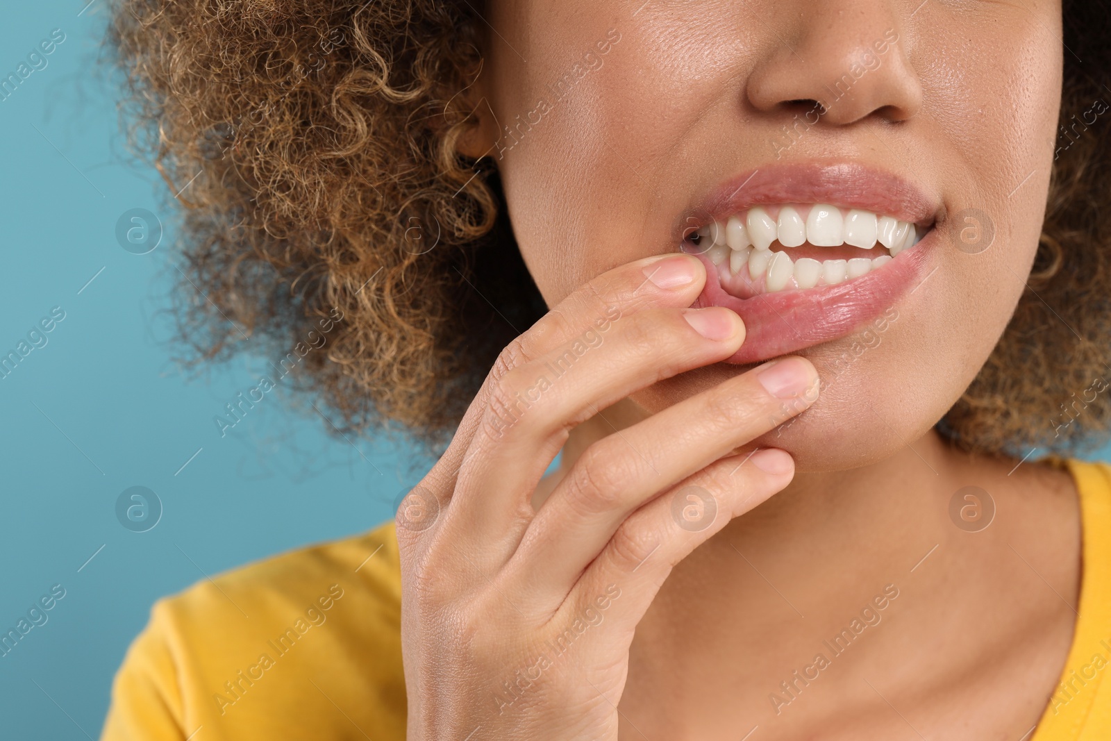 Photo of Woman showing her clean teeth on light blue background, closeup