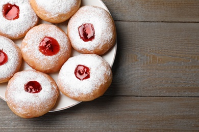 Photo of Hanukkah doughnuts with jelly and sugar powder served on wooden table, top view. Space for text