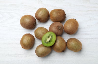 Photo of Cut and whole fresh kiwis on white wooden table, flat lay