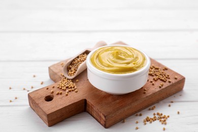 Bowl with delicious mustard and seeds on white wooden table