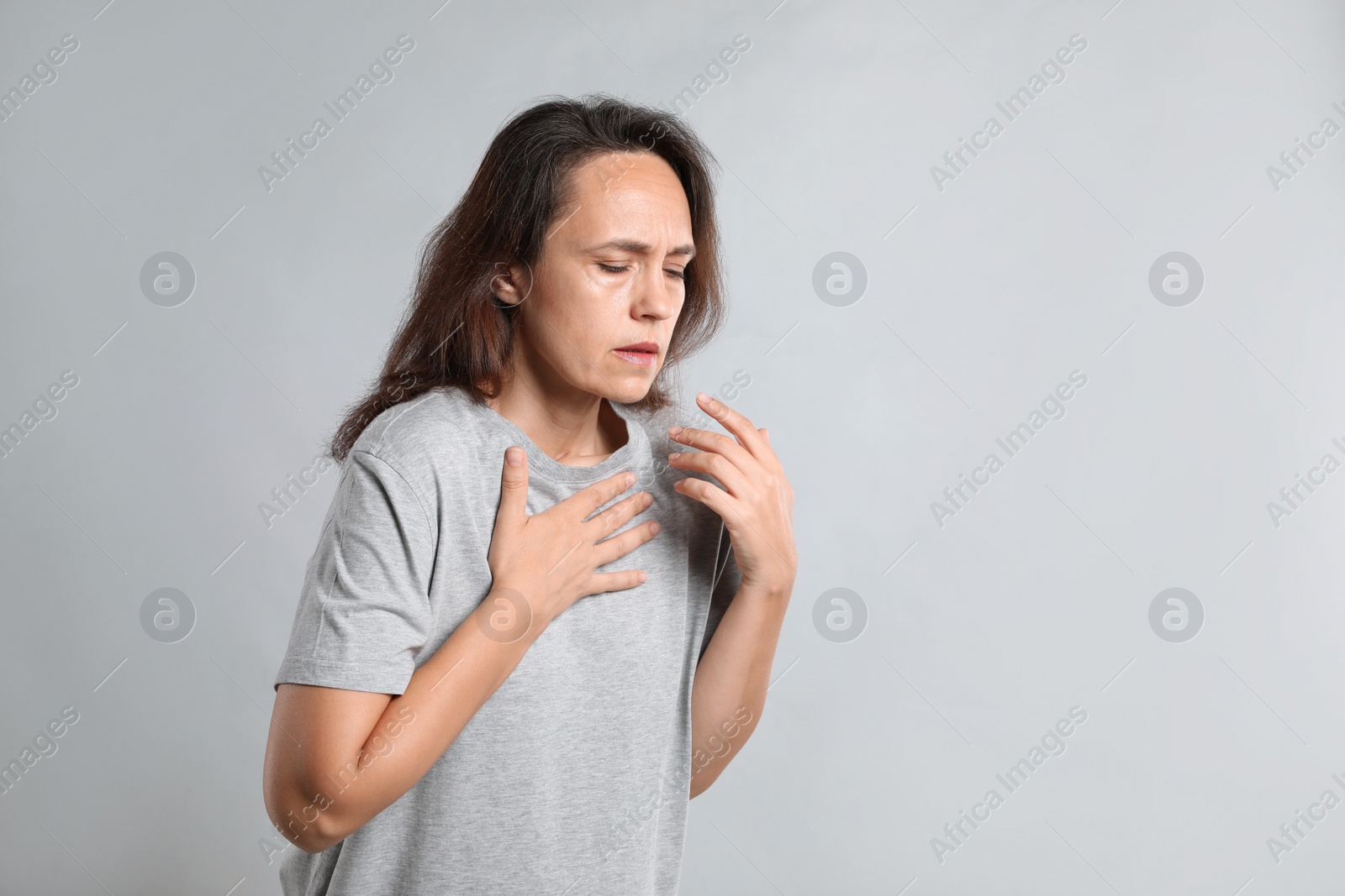 Photo of Mature woman suffering from breathing problem on light background. Space for text