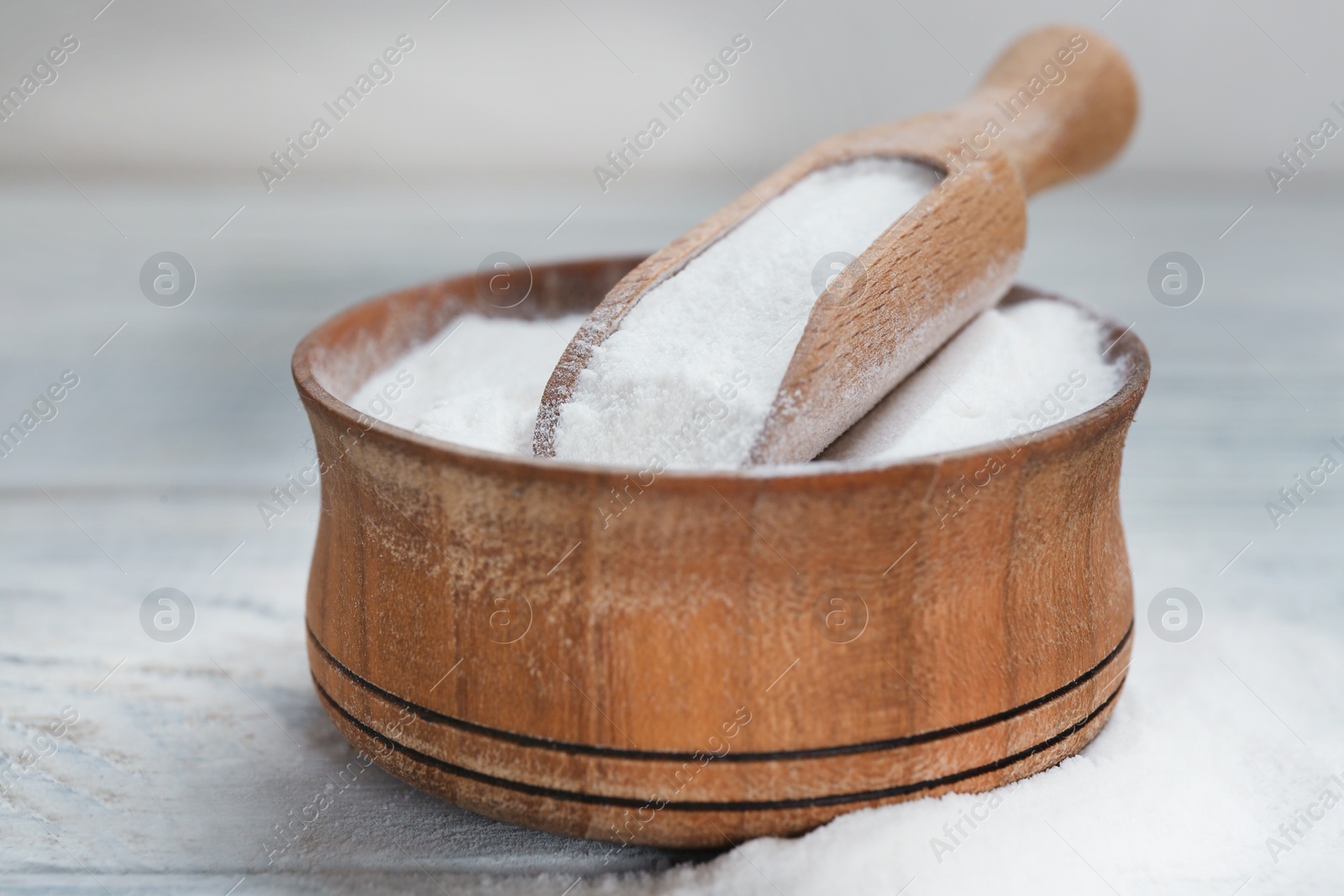 Photo of Bowl and scoop with baking soda on white wooden table