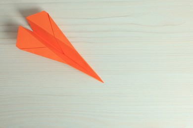 Photo of Handmade orange paper plane on beige wooden table, top view. Space for text