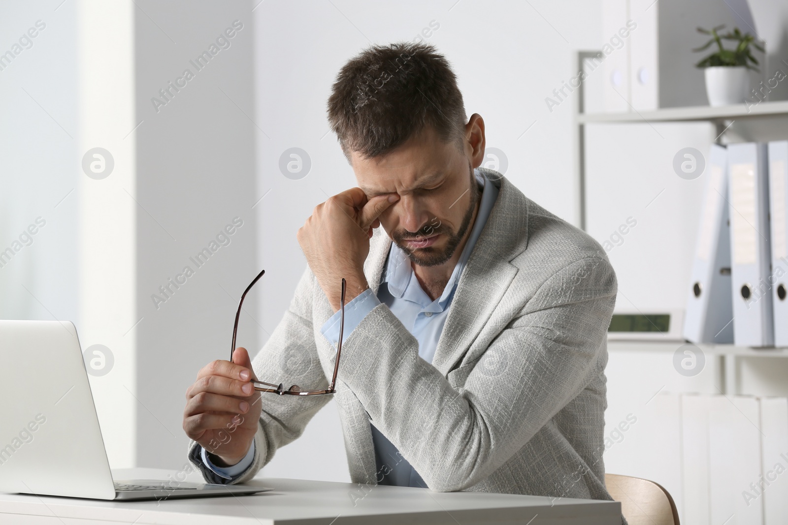 Photo of Man suffering from eyestrain at desk in office