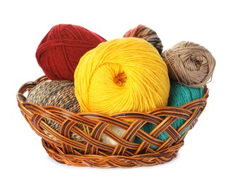 Different balls of woolen knitting yarns in wicker basket on white background