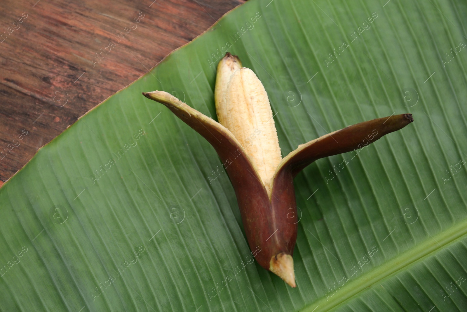 Photo of Delicious purple banana and fresh leaf on wooden table, top view