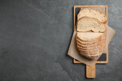 Board with cut bread on grey table, top view. Space for text