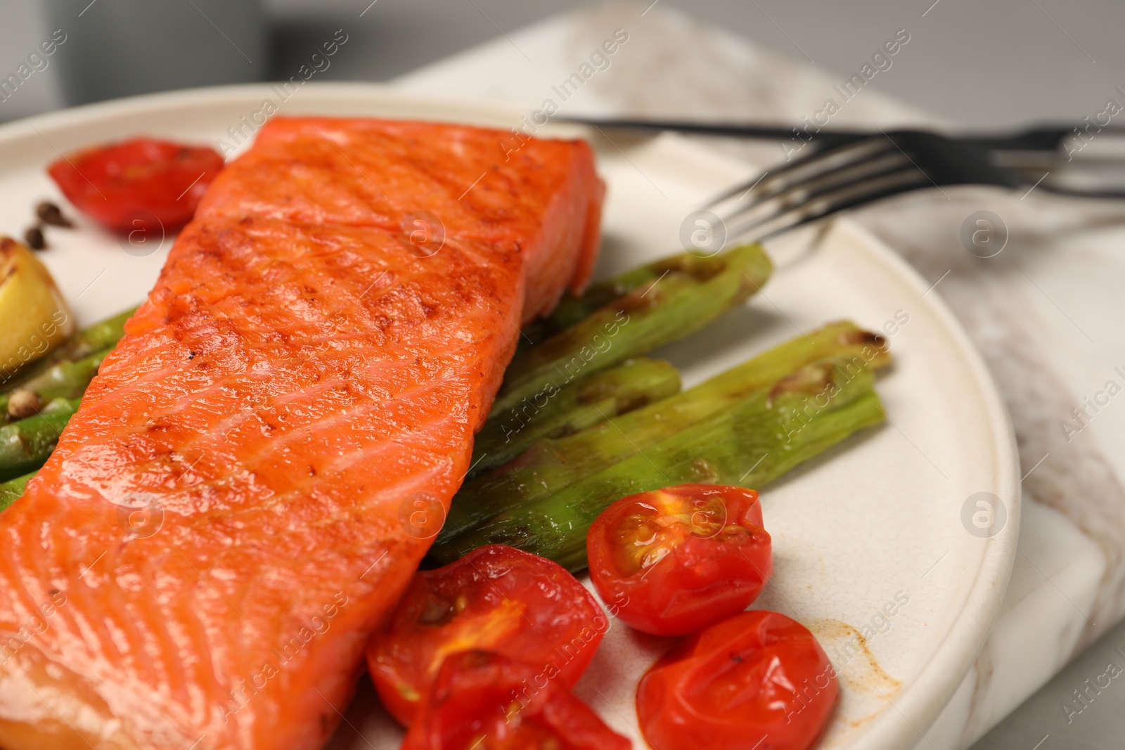 Photo of Tasty grilled salmon with asparagus and tomatoes on table, closeup