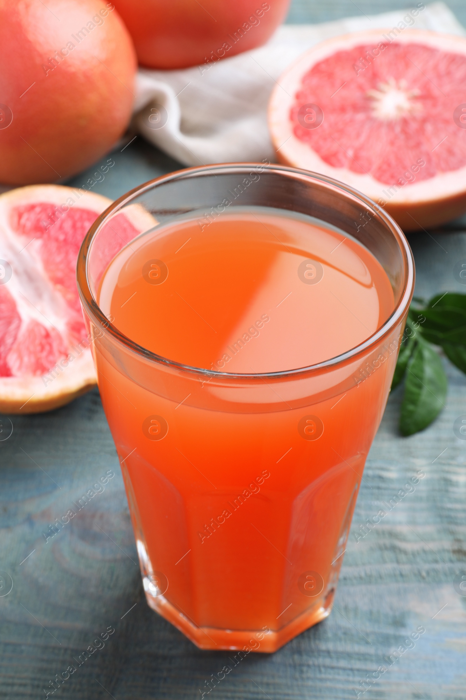 Photo of Tasty freshly made grapefruit juice on blue wooden table