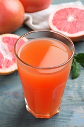 Photo of Tasty freshly made grapefruit juice on blue wooden table