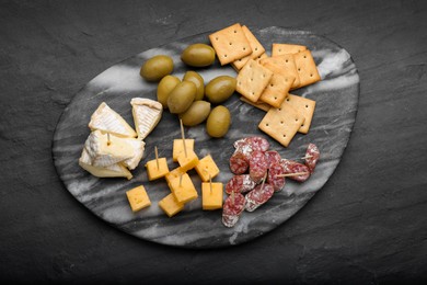 Toothpick appetizers. Pieces of cheese, sausage and olives on black table, top view
