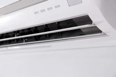 Modern air conditioner on white wall indoors, closeup view