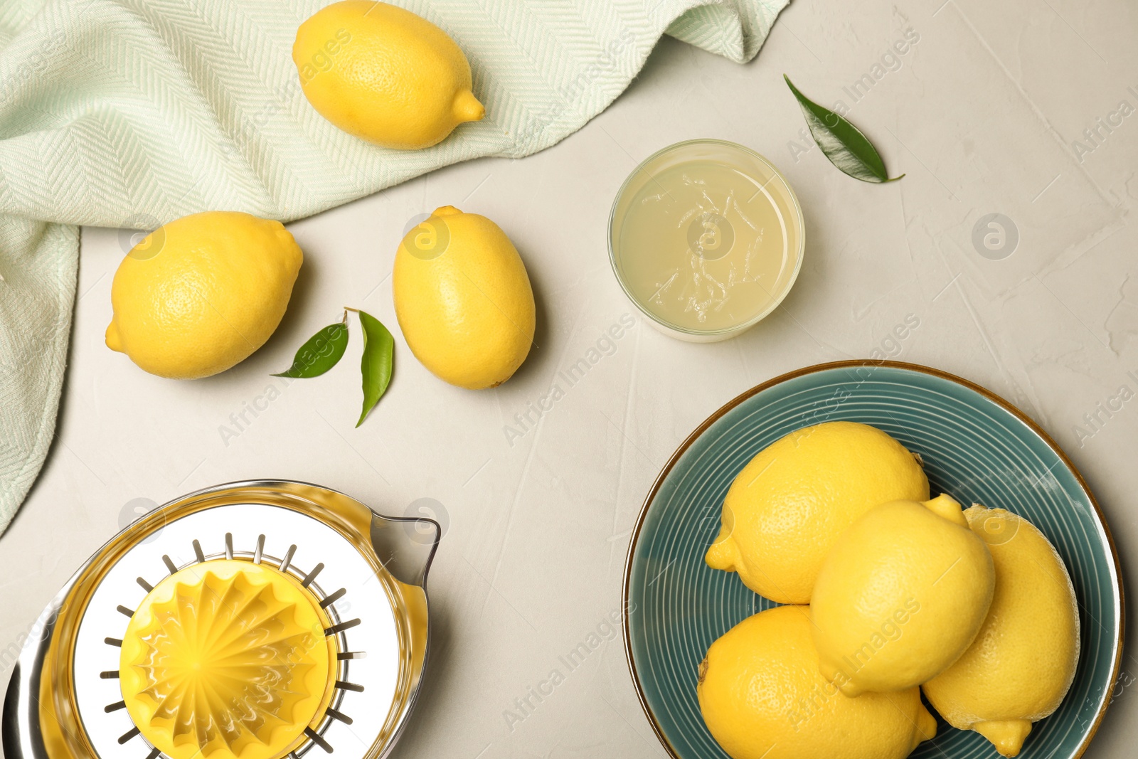 Photo of Composition of fresh lemons, juice and squeezer on table, top view