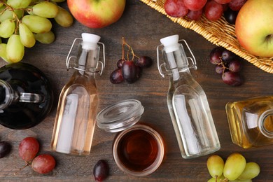 Photo of Different types of vinegar and fresh fruits on wooden table, flat lay