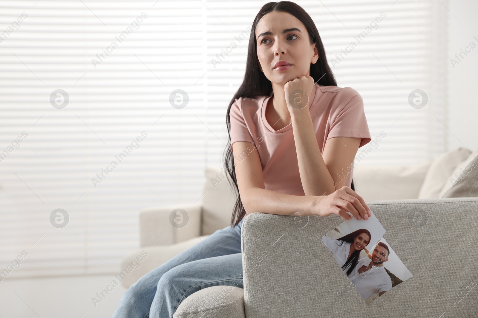 Photo of Upset woman holding torn photo at home, space for text. Divorce concept