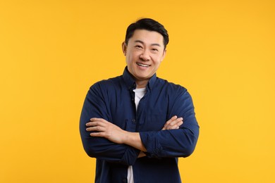 Portrait of happy man with crossed arms on yellow background