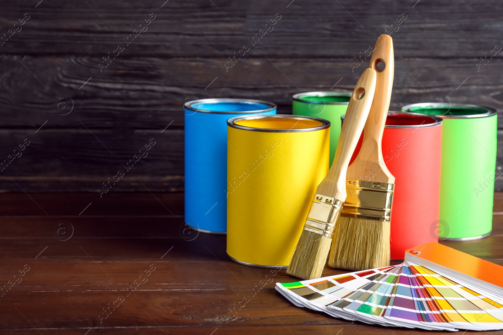Photo of Paint cans, brushes and color palette sample on table against wooden background. Space for text