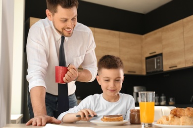 Photo of Dad and son having breakfast together in kitchen