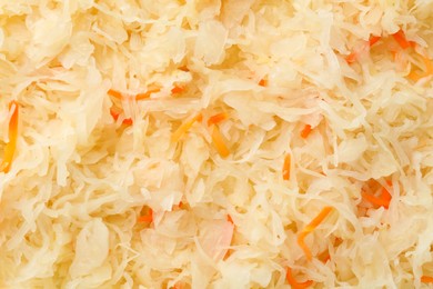 Photo of Tasty fermented cabbage with carrot as background, top view