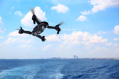 Image of Modern drone flying over sea and blurred cityscape on background. Aerial survey