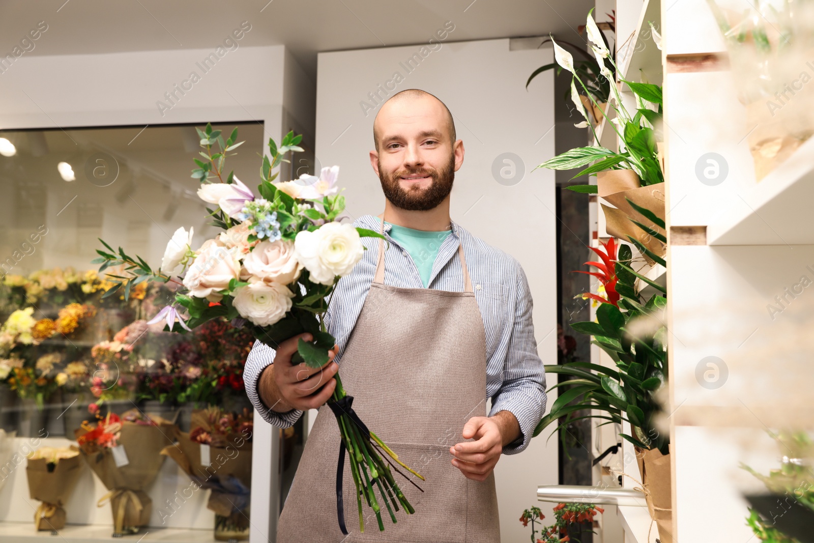 Photo of Professional florist with bouquet of fresh flowers in shop