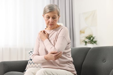 Arthritis symptoms. Woman suffering from pain in elbow at home