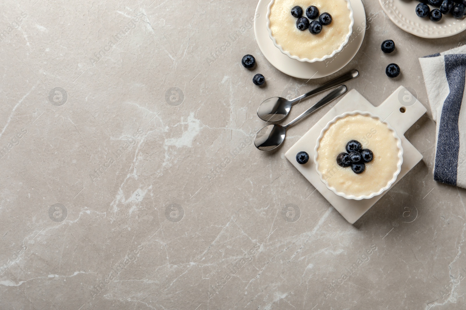 Photo of Delicious semolina pudding with blueberries on marble table, flat lay. Space for text