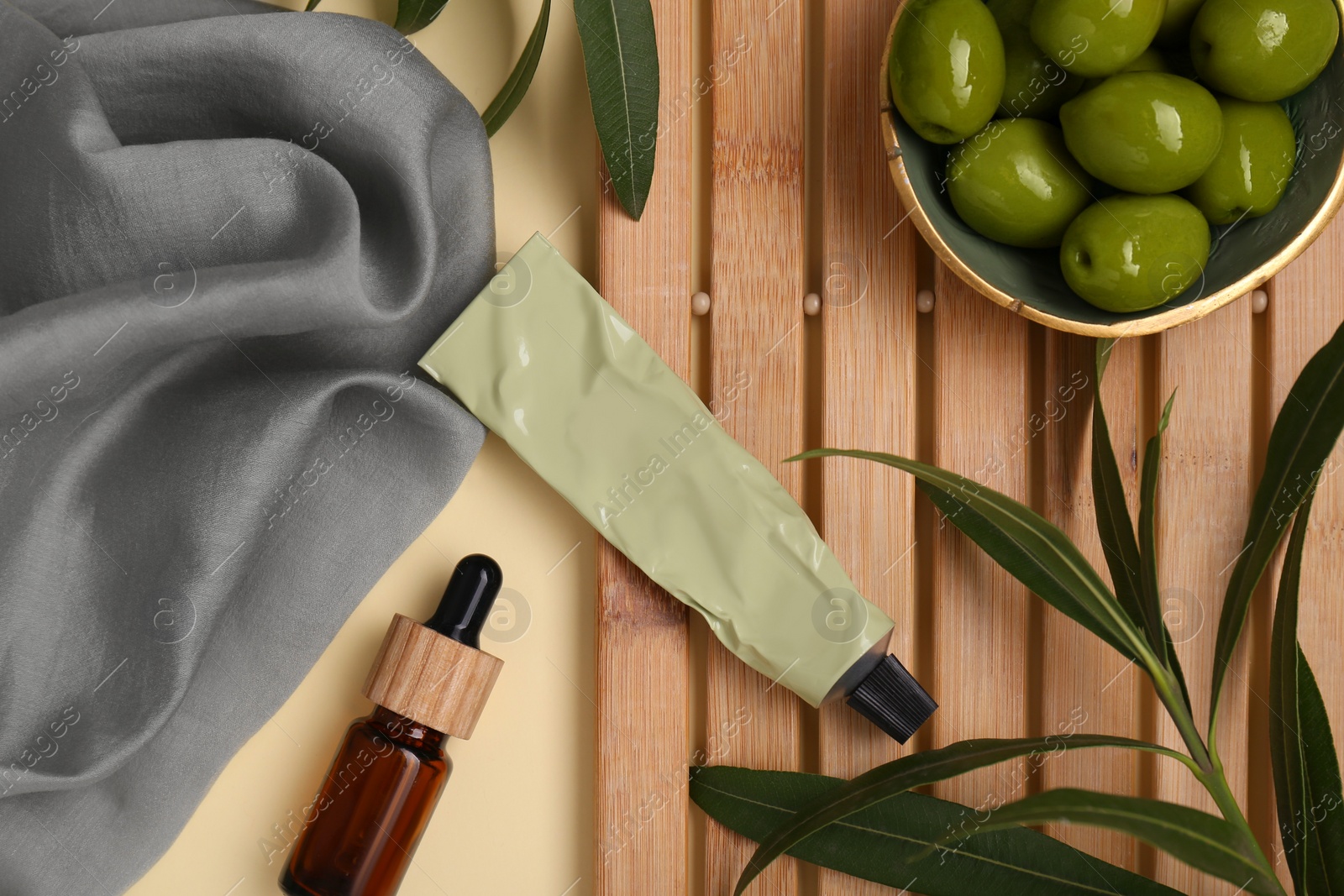 Photo of Cosmetic products with olive essential oil and leaves beige background, flat lay