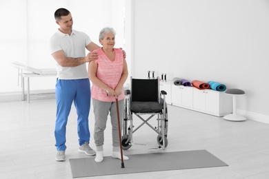 Professional physiotherapist working with elderly patient in rehabilitation center. Space for text