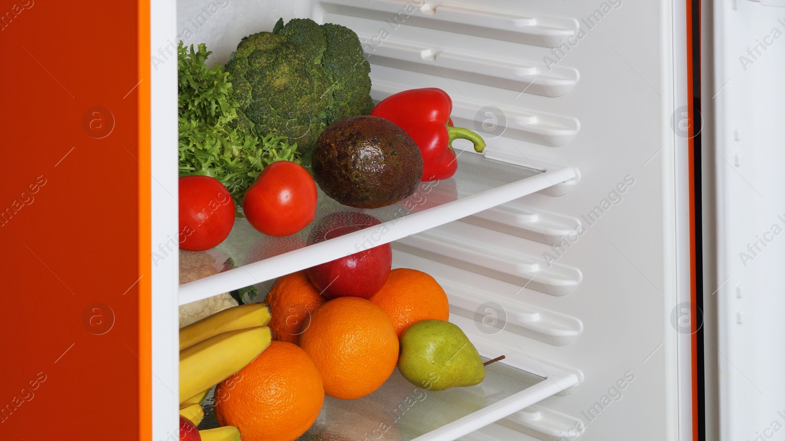 Photo of Open refrigerator with many different fresh vegetables and fruits
