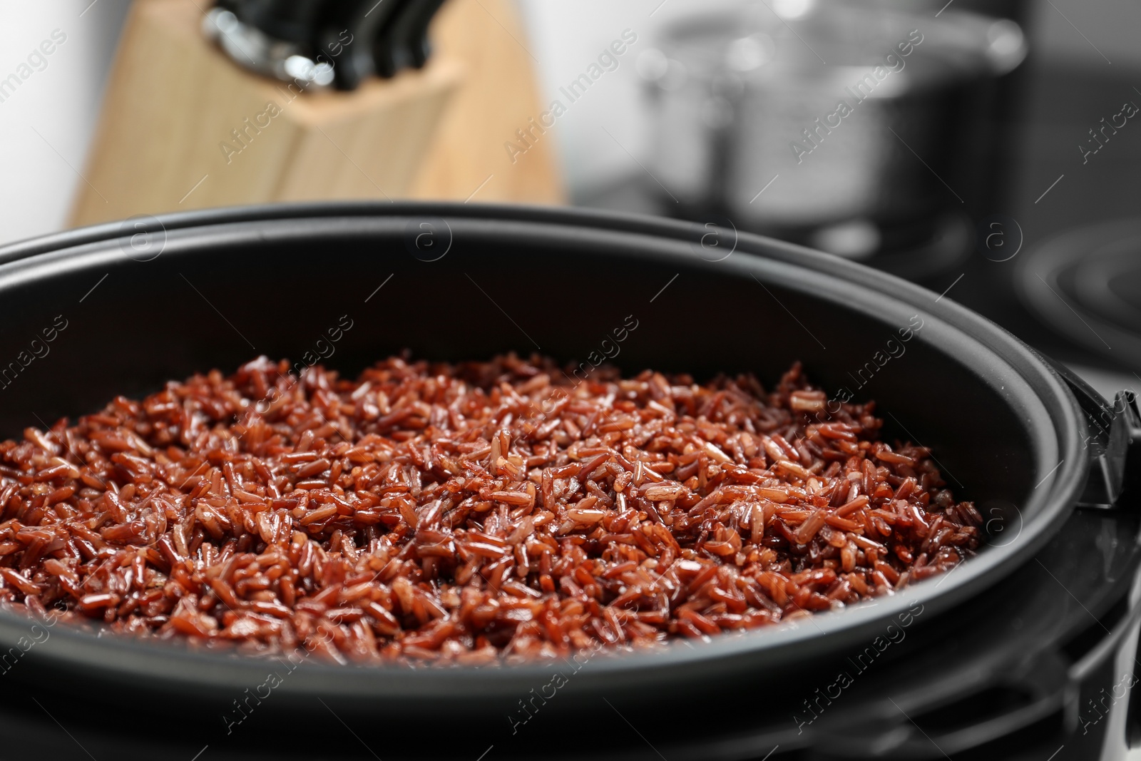 Photo of Modern multi cooker with boiled brown rice in kitchen, closeup