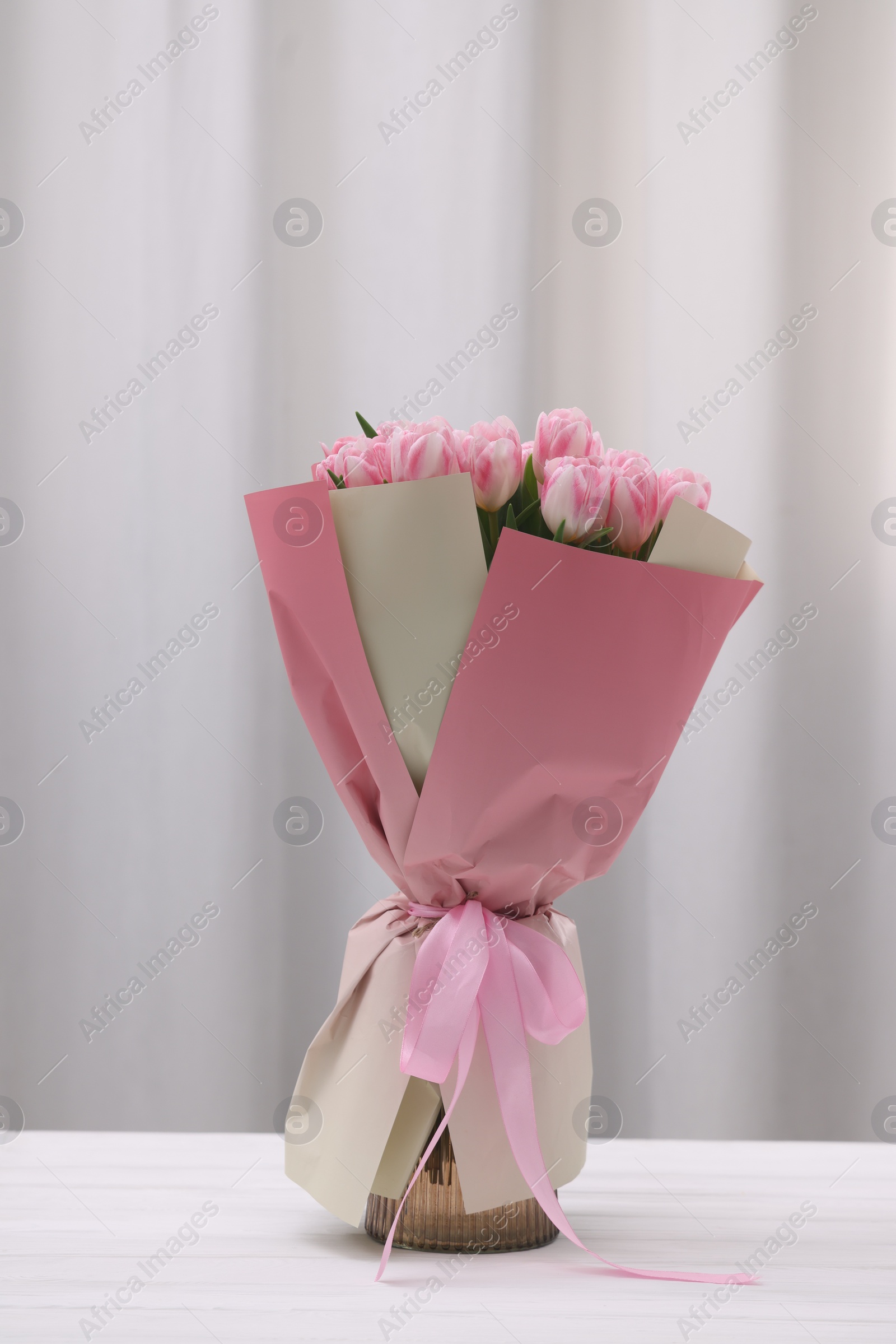 Photo of Beautiful bouquet of fresh pink tulips on table indoors