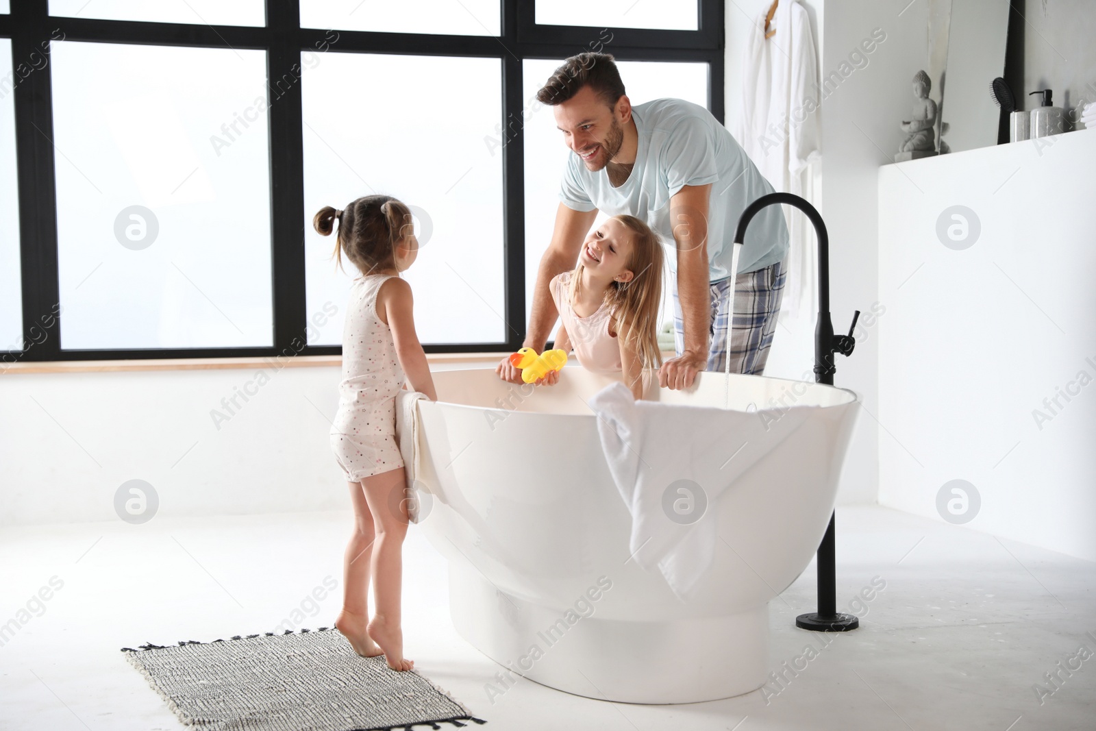 Photo of Young father with little daughters in bathroom