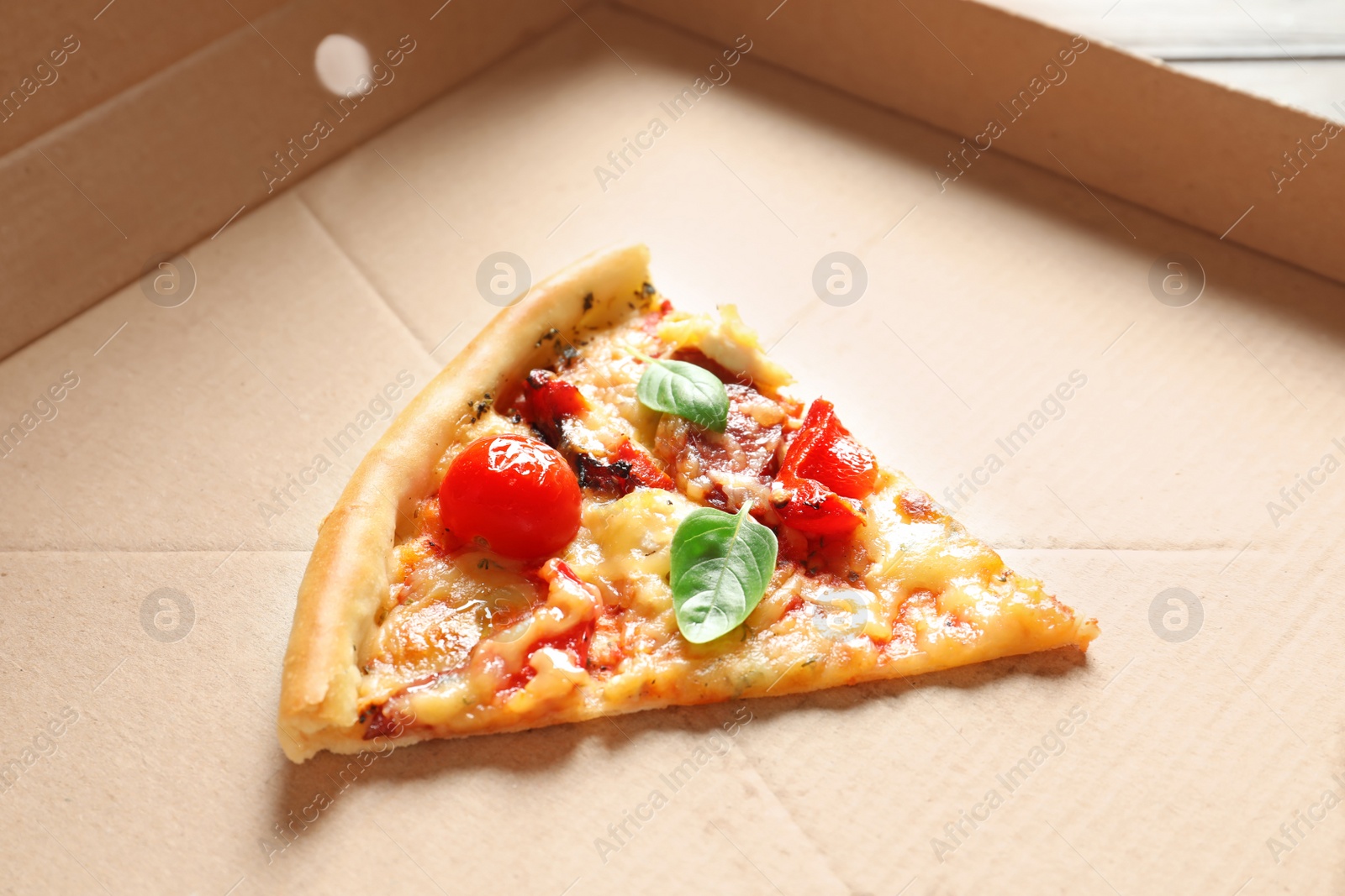 Photo of Last slice of tasty pizza with tomatoes and sausages in cardboard box
