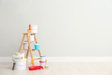 Photo of Decorator's kit of tools and paints near light wall indoors. Space for text