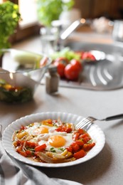 Plate of tasty fried eggs with vegetables on table in kitchen. Space for text