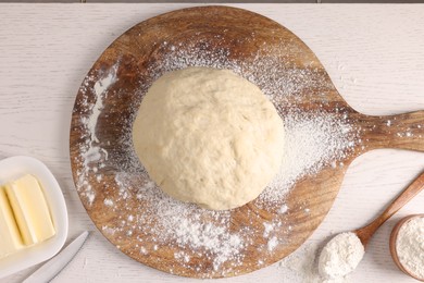 Fresh dough sprinkled with flour and other ingredients on white wooden table, flat lay