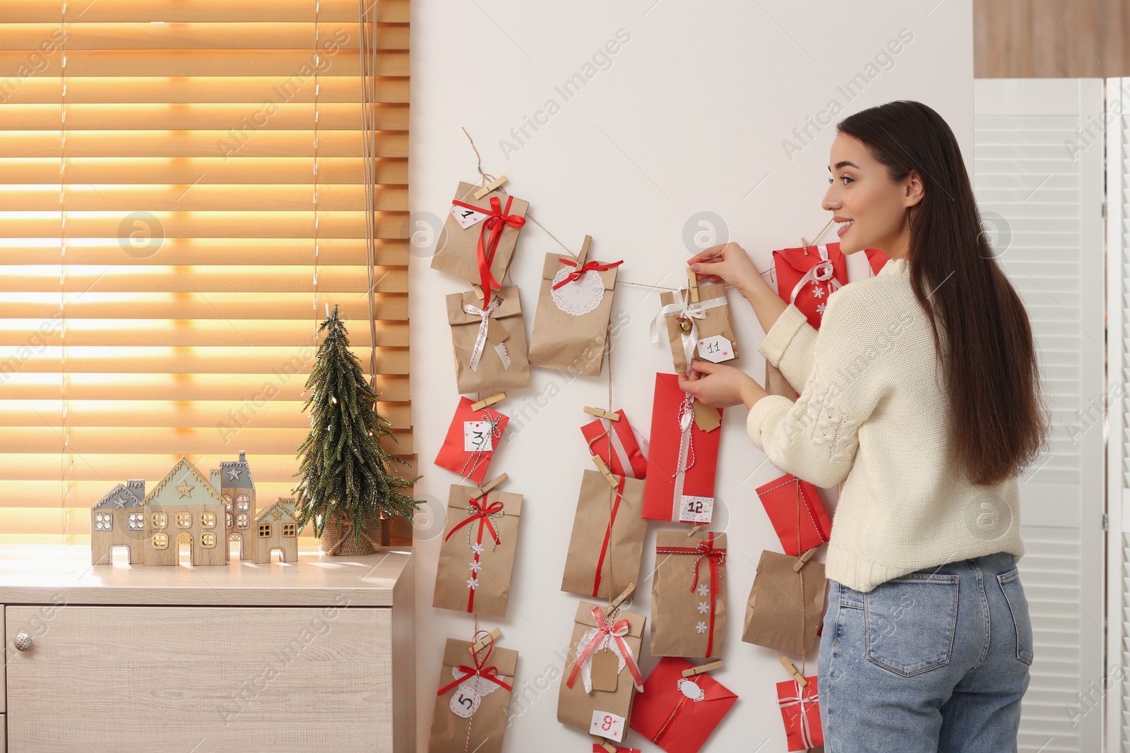 Photo of Woman taking gift from Advent calendar at home, back view. Christmas tradition