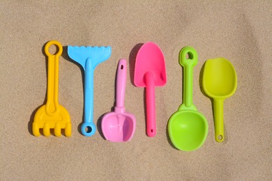 Photo of Set of colorful beach toys on sand, flat lay