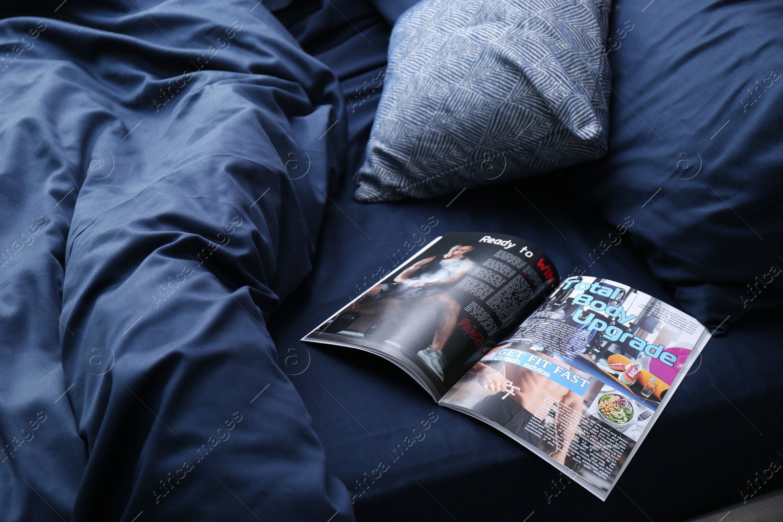 Photo of Open magazine on bed with stylish silky linens