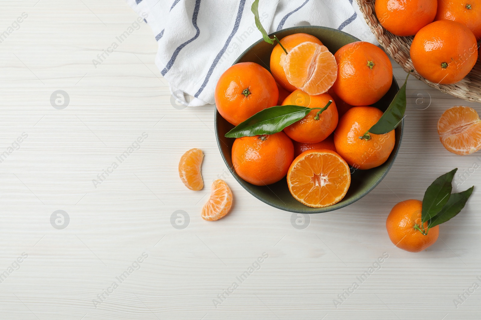 Photo of Delicious tangerines with green leaves on white wooden table, flat lay. Space for text