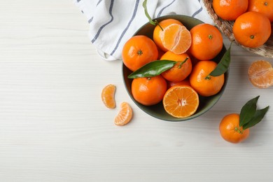 Delicious tangerines with green leaves on white wooden table, flat lay. Space for text