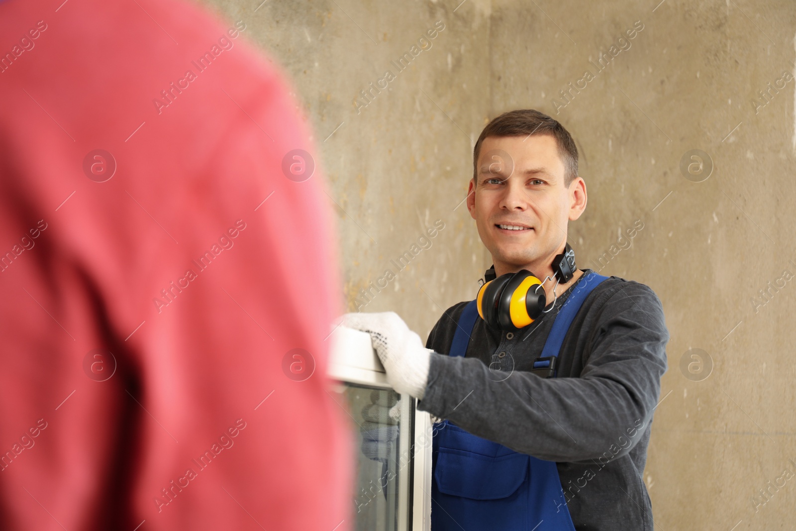 Photo of Workers in uniform with new plastic window indoors