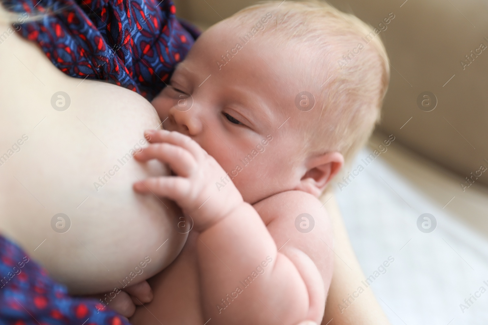 Photo of Woman breast feeding her little baby at home, closeup