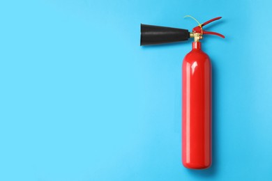 Photo of Fire extinguisher on light blue background, top view. Space for text
